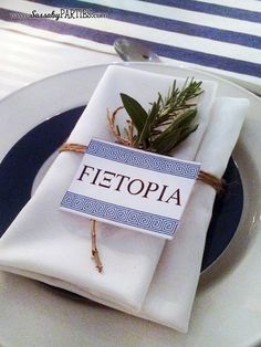 a place setting with napkins, silverware and an olive branch wrapped in twine