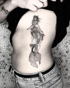 a woman's stomach with a tattoo on her belly and an image of a mermaid