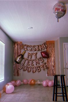 a party room with balloons and streamers on the wall, including a sign that says kissing my years agody