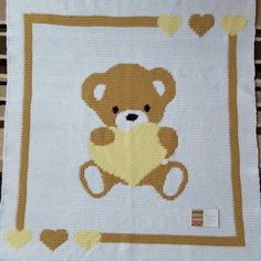 a cross stitch teddy bear on a white blanket