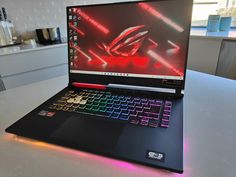 a laptop computer sitting on top of a table with a red and black keyboard in front of it