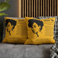 two yellow pillows with the words draw me on them sitting on a couch next to a potted plant