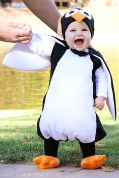 a baby in a penguin costume being held by an adult