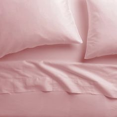 a bed with pink sheets and pillows on it