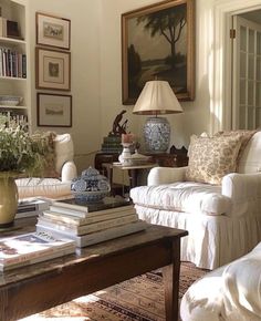 a living room filled with furniture and books on top of a coffee table in front of a painting