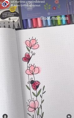 an open notebook with flowers and ladybug drawn on the pages next to colored crayons