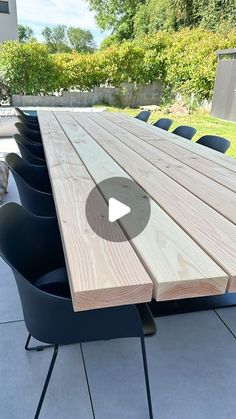 a wooden table sitting on top of a patio next to blue chairs and a dog