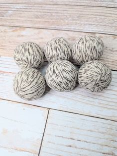 six balls of yarn sitting on top of a white wooden floor next to each other