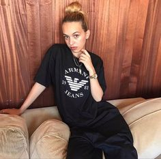 a woman sitting on top of a couch next to a wooden wall