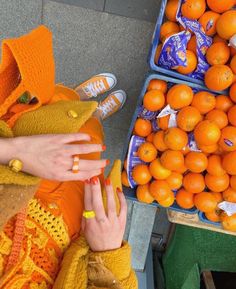 a woman with her hand on an orange in front of some boxes of oranges