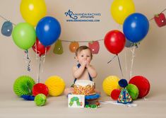 a baby sitting in front of a cake surrounded by balloons