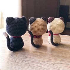 three small crocheted cats sitting on top of a wooden table next to each other