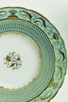 two blue and gold plates sitting side by side on top of each other with designs