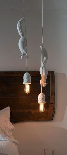 three light bulbs are hanging from the ceiling above a bed with white sheets and pillows