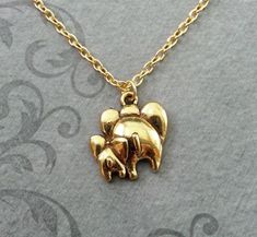 This listing is for a gold-colored mama and baby elephant necklace. This little guy is so cute! You'll be able to choose your chain length and style at checkout by using the "Chain Length/Style" drop-down menu. **Please see the second photo for scale! This is a SMALL charm. If you're on the mobile site, just swipe to the side. :)**Please note that this is gold-colored and NOT actually made from real gold. :)- - - - - - -This is our third shop for jewelry. If you're looking for something a bit mo Gold Novelty Charm Necklaces For Gifts, Gold Novelty Charm Necklace For Gifts, Cute Gold Jewelry For Mother's Day, Cute Gold Necklaces For Mother's Day, Cute Gold Necklace For Mother's Day, Cute Gold Necklace For Mom, Cute Gold Jewelry For Mom's Gift, Cute Gold Jewelry Gift For Mom, Cute Gold Jewelry As Gift For Mom