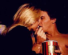 a man and woman kissing while holding a coffee cup