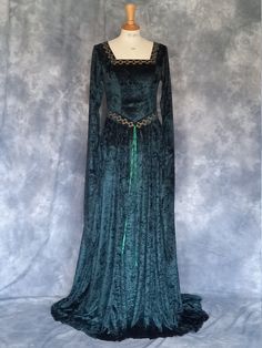 Cordelia, a  Celtic Inspired Medieval, Pre- Raphaelite,Renaissance Gown, Handfasting Gown with Celtic Embroidery. Pictured here in olive green crushed velvet with old gold embroidery. Many colour choices available.   For full range of colours go to www.frockfollies.com FREE INSURED AND TRACKABLE SHIPPING PERFECT FOR SO MANY OCCASIONS: GOTHIC EVENTS MEDIEVAL/RENAISSANCE/ELVISH WEDDINGS LARP EVENTS RE ENACTMENTS HANDFASTING CEREMONIES LARP EVENTS YOUR INNER GODDESS MOMENTS! HAND MADE IN ENGLAND BY AN EXPERIENCED THEATRICAL COSTUMIER THIS OUTFIT IS AVAILABLE TO ORDER IN A WIDE RANGE OF COLORS AND CUSTOM MADE TO YOUR OWN MEASUREMENTS. frockfollies PRIDES ITSELF ON QUALITY OF WORKMANSHIP AND ATTENTION TO DETAIL. THIS ELEGANT FLOWING DRESS IS  MADE IN A LUXURIOUS SOFT DRAPEY  OLIVE GREEN CRUSHED Traditional Dresses For Medieval Festivals Weddings, Traditional Wedding Dresses For Medieval Festivals, Floor-length Medieval Dress For Costume, Medieval Gown With Historical Design For Costume Party, Medieval Costume Gown With Historical Design, Medieval Gown For Costume Party, Fitted Green Dress For Medieval Festivals, Fitted Medieval Floor-length Gown, Medieval Style Fitted Floor-length Gown