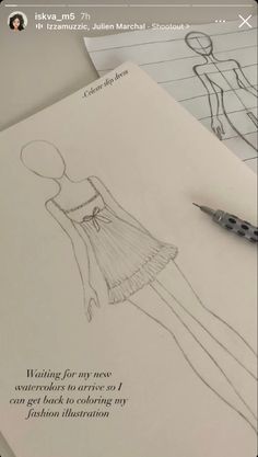 a drawing of a woman's dress on paper next to a pen