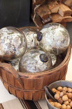 a basket filled with lots of silver balls next to a bowl full of nuts on top of a table