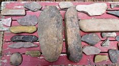 several different types of rocks laid out on a wooden table with pink paint and wood planks