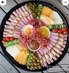 a platter with meats, cheeses and vegetables on it is shown here