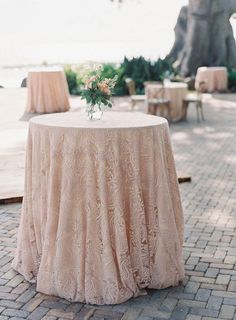 the table is set up for an outdoor wedding reception with flowers in a vase on top