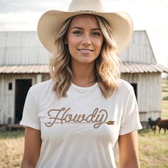 Howdy t-shirt for country girls and cowgirls is a Next Level brand tee and comes in unisex cut and sizes. This graphic tee features the popular rope font Howdy with a rustic arrow underscore. A vintage style graphic for the modern cowgirl. Looks perfect alone or layered under a chic blazer for a more sophisticated look. The perfect shirt for the rodeo, country music concert, a bachelorette party in Nashville or around town. Our graphic tees are super soft and super comfy! Unisex sizing. This uni Country Style T-shirt For Western-themed Summer Events, Country Style Short Sleeve T-shirt For Rodeo, Country Style Short Sleeve T-shirt For Ranch, Short Sleeve T-shirt For Country Events, Bachelorette Party In Nashville, Rope Font, Country Music Concert, Nashville Bachelorette Party, Country Music Concerts