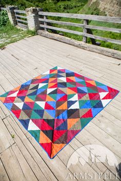 a multicolored quilt on a wooden deck