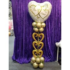 a balloon in the shape of a heart with vines and hearts attached to it, hanging from a purple curtain