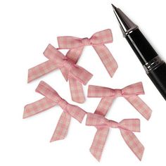 three pink bows tied around a fountain pen