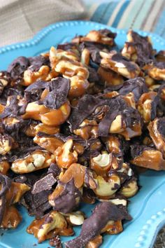 a blue plate topped with lots of chocolate and nuts covered in caramel sauce on top of a table