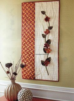 a vase filled with flowers next to a wall hanging