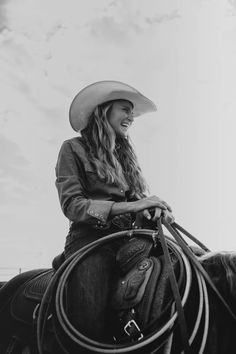 a black and white photo of a woman wearing a cowboy hat sitting on a horse