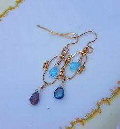 "Original Blue Topaz Labradorite, 14K Gold Filled Earrings. The Labradorite and Blue Topaz are a lovely complement to each other. Uniquely created of Gold Filled Wires, Handmade wire wrapped gemstones, and hammered in my home studio in Florida. 14K Gold Filled Wire is Nickle Free.2 5/8\" inches long by 7/8\" inches wide. These earrings have classic lines and are perfect for day wear or a special evening out. These earrings come with soft silicone earring backs. These Beautiful handmade pair of e Wire Wrapped Briolette Earrings For Anniversary, Blue Briolette Wire Wrapped Earrings, Wrapped Gemstones, Jewelry Gold Earrings, Green Amethyst Earrings, Labradorite Earrings, Blue Topaz Earrings, Handmade Wire Wrapped, Topaz Earrings