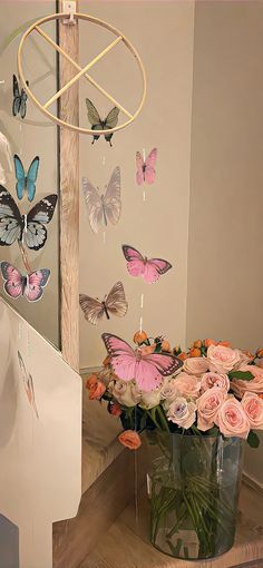 a vase filled with pink roses sitting on top of a wooden table next to a mirror