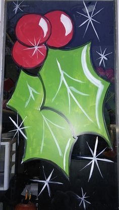 a christmas decoration with holly leaves and red balls on the front door glass window,