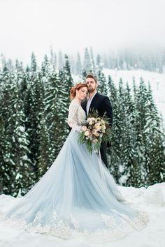 a bride and groom standing in the snow with evergreen trees behind them at their wedding