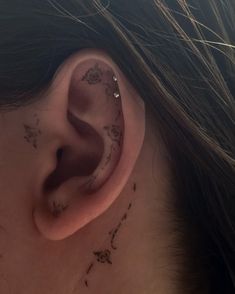 a woman's ear with small tattoos on it