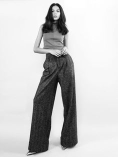 a woman standing in front of a white background wearing wide legged pants and a tank top