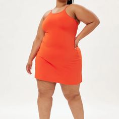 a woman in an orange dress poses for the camera with her hands on her hips