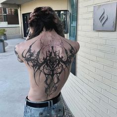 a woman with black ink on her back standing in front of a building and looking out the window