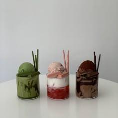 three different types of ice creams in small containers on a table with sticks sticking out of them