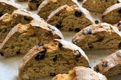 several pieces of bread sitting on top of a white paper covered tray with raisins and chocolate chips