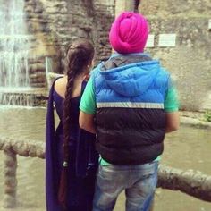 two people standing next to each other in front of a waterfall with pink hair and blue vests