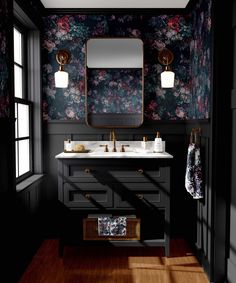 a black and white bathroom with red flowers on the wall, gold fixtures and two sinks