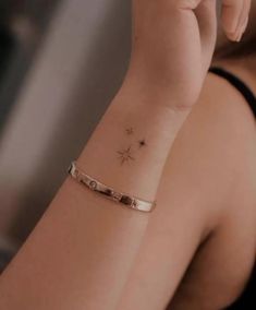 a woman is holding her hand up to her face while wearing a bracelet with stars on it