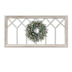 a christmas wreath hanging on the side of a window sill with pine cones and greenery