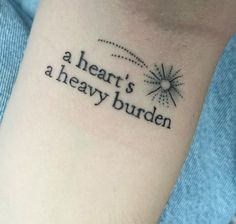 a tattoo saying a heart's a heavy burden on the wrist is shown in black ink