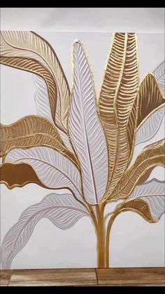 a white and gold painting on the wall with leaves in it's centerpiece