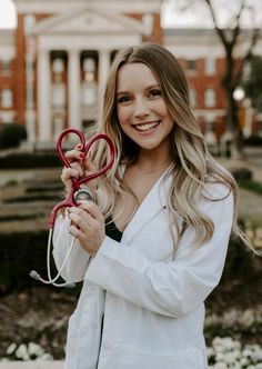 a woman holding a pair of scissors in front of a building